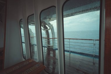 Cruise ship Open deck with Rescue Lifeboats and life buoy through the Window in raindrops