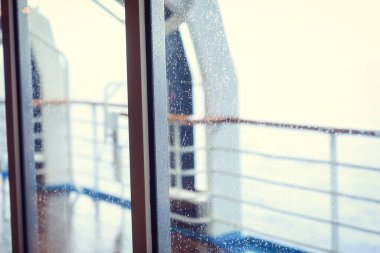 Cruise ship Open deck with Rescue Lifeboats and life buoy through the Window in raindrops
