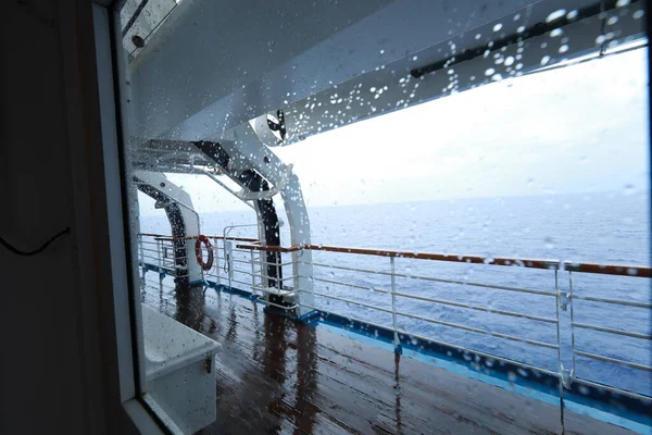 Cruise ship Open deck with Rescue Lifeboats and life buoy through the Window in raindrops
