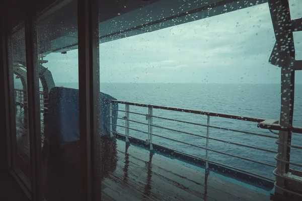 Cruise ship Open deck with Rescue Lifeboats and life buoy through the Window in raindrops