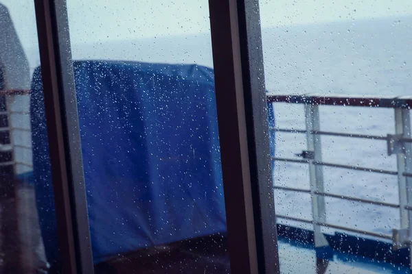 Cruise ship Open deck with Rescue Lifeboats and life buoy through the Window in raindrops