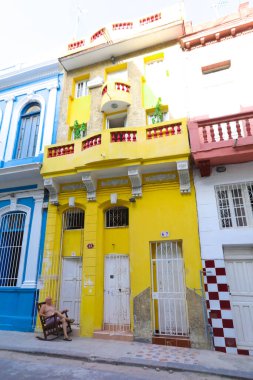 Havana şehir merkezinde klasik eski arabaların ve geleneksel renkli binaların olduğu sokak sahnesi