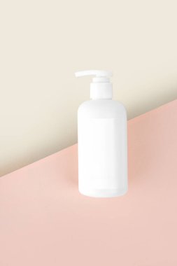 Banyo yapan çocuklar için doğal hipoalerjenik köpük. Beyaz plastik pompa şişesi. Çocuk kozmetiği. Bej pembe arka planda şişeler. Dikey. Boşluğu kopyala.