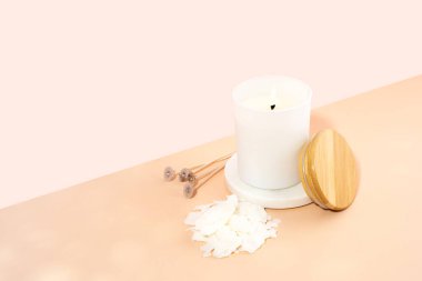 Organik kokulu soya mumu, bej pembe arka planda beyaz seramik kavanozda fitil. Moda, el yapımı konsept. Minimalizm. İzometrik projeksiyon. kopyalama alanı. Yatay.