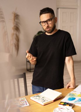 Sanatçı işini bir müdahaleci ile tartışıyor. Bir atölyede masanın başında duran genç bir adam. Sanatçının stüdyosunda çalışırken ilham alma süreci bulanıklaştı..