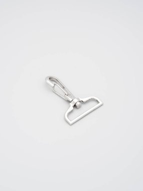 Gri arka planda duran çantalar ve sırt çantaları için metal ıstakoz pençesi tokası yığını. Krom kaplama metal aksesuarlar ve çantalar ve sırt çantaları için malzeme. El çantaları, kopyalama alanı.