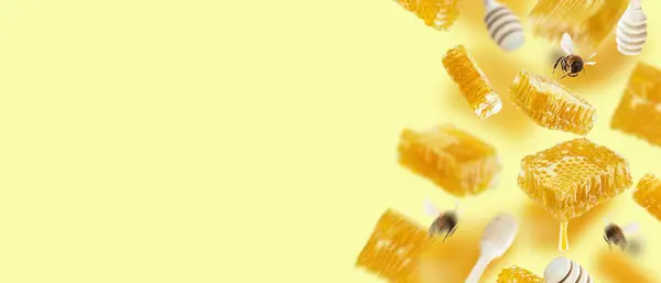 A set of floating honeycombs, honey dippers and flying bees on a yellow background. Conceptual composition with honey. Creative layout design. Copy space, banner.