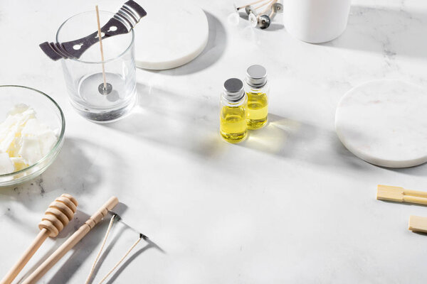 Набор инструментов для домашнего натурального экологически чистого соевого воска свечи, фитиль, духи, эфирное масло на мраморном столе. Процесс изготовления. Модный дом. Малый бизнес, арт-продукция.