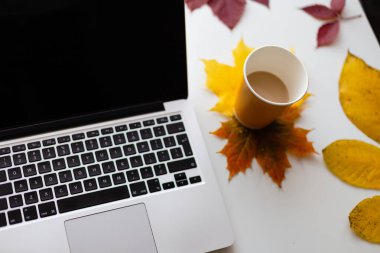 Bir dizüstü bilgisayar, bir fincan kahve ve sonbahar yaprakları. Üst görünüm.