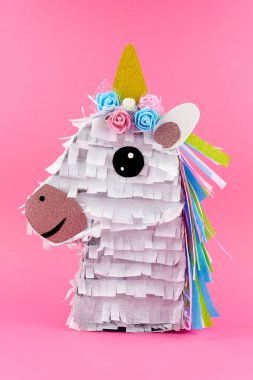 Pembe arka planda el yapımı renkli tek boynuzlu at Pinata.