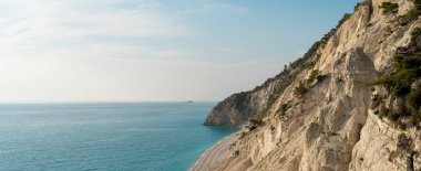 Güzel, vahşi Akdeniz çakıl taşı plajı büyük bir uçurumun altında.