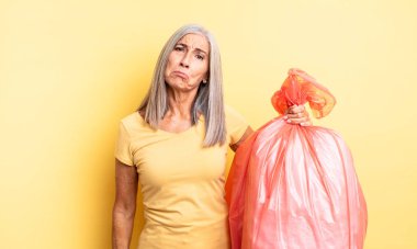 Orta yaşlı, güzel bir kadın üzgün ve mızmızlanıyor. Mutsuz bir bakışı var ve ağlıyor. Plastik çöp torbası.