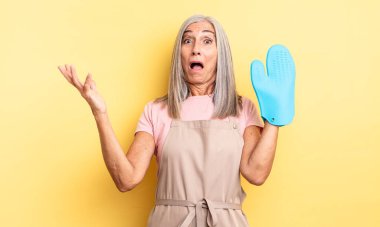 Orta yaşlı, güzel bir kadın inanılmaz bir sürprizle şaşkına dönmüş ve hayrete düşmüştü. fırın eldiveni kavramı