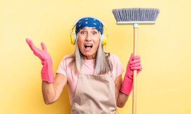 Orta yaşlı güzel bir kadın son derece şaşkın ve şaşırmış hissediyor. ev ve süpürge kavramı