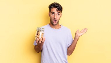 İspanyol yakışıklı adam şaşırmış ve şok olmuş görünüyor. Çenesi düşmüş ve elinde bir nesne var. kurabiye konsepti