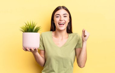 Genç İspanyol kadın şokta, gülüyor ve başarıyı kutluyor. bitki otu konsepti