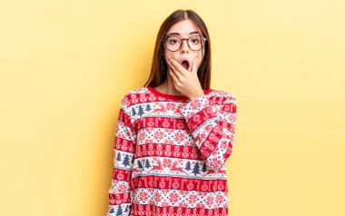 Ağzı ve gözleri sonuna kadar açık ve eli çenesinde olan genç İspanyol kadın. Chistmas ve yeni yıl konsepti