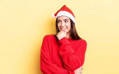 Genç İspanyol kadın mutlu ve kendinden emin bir ifadeyle gülümsüyor. Elleri çenesinde. Chistmas ve yeni yıl konsepti