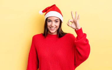 Genç İspanyol kadın kendini mutlu hissediyor, iyi bir jestle onaylıyor. Chistmas ve yeni yıl konsepti