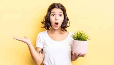 Genç İspanyol kadın şaşırmış ve şok olmuş görünüyor. Çenesi düşmüş ve elinde bir nesne tutuyor. büyüme kavramı