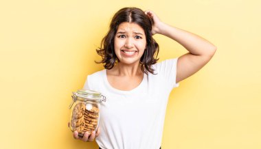 Genç İspanyol kadın stresli, endişeli ya da korkmuş hissediyor, elleri başının üstünde. kurabiye şişesi konsepti