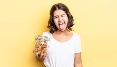 Neşeli ve asi tavırları olan, şaka yapan ve dilini dışarı çıkaran genç İspanyol bir kadın. kurabiye şişesi konsepti