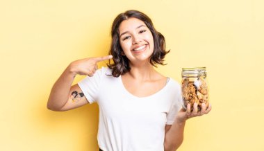 Genç İspanyol kadın kendine güvenerek gülümsüyor ve kendi gülüşünü gösteriyor. kurabiye şişesi konsepti