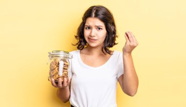 Genç İspanyol kadın kapiş ya da para hareketi yapıyor, sana ödemeni söylüyor. kurabiye şişesi konsepti