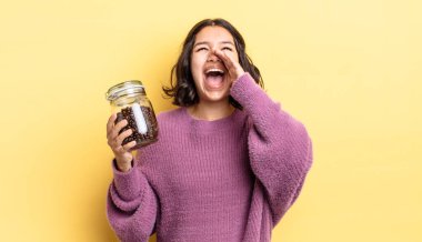 Genç İspanyol kadın kendini mutlu hissediyor, elleri ağzının kenarında bağırıyor. kahve çekirdeği konsepti