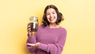 Genç İspanyol kadın neşeyle gülümsüyor, mutlu hissediyor ve bir konsept gösteriyor. kahve çekirdeği konsepti