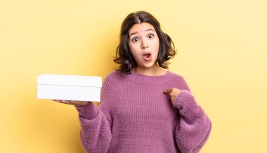 Genç İspanyol kadın şok olmuş ve ağzı açık, kendini işaret ederek şaşırmış görünüyor. boş kutu kavramı