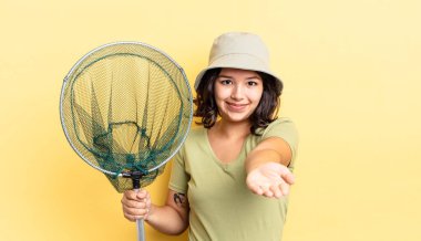 Genç İspanyol kadın mutlu bir şekilde gülümsüyor ve bir konsept sunuyor. balıkçı ağı kavramı