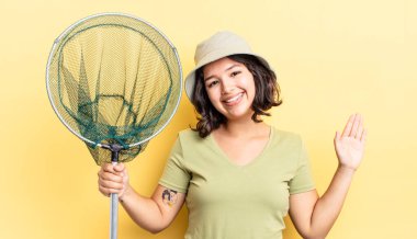 Genç İspanyol kadın mutlu bir şekilde gülümsüyor, el sallıyor, sizi selamlıyor ve selamlıyor. balıkçı ağı kavramı