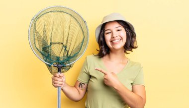 Genç İspanyol kadın neşeyle gülümsüyor, mutlu hissediyor ve bir tarafı işaret ediyor. balıkçı ağı kavramı