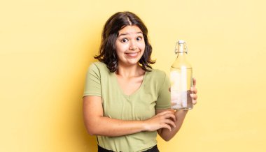 Genç İspanyol kadın omuz silkiyor, kafası karışık ve kararsız. su şişesi kavramı