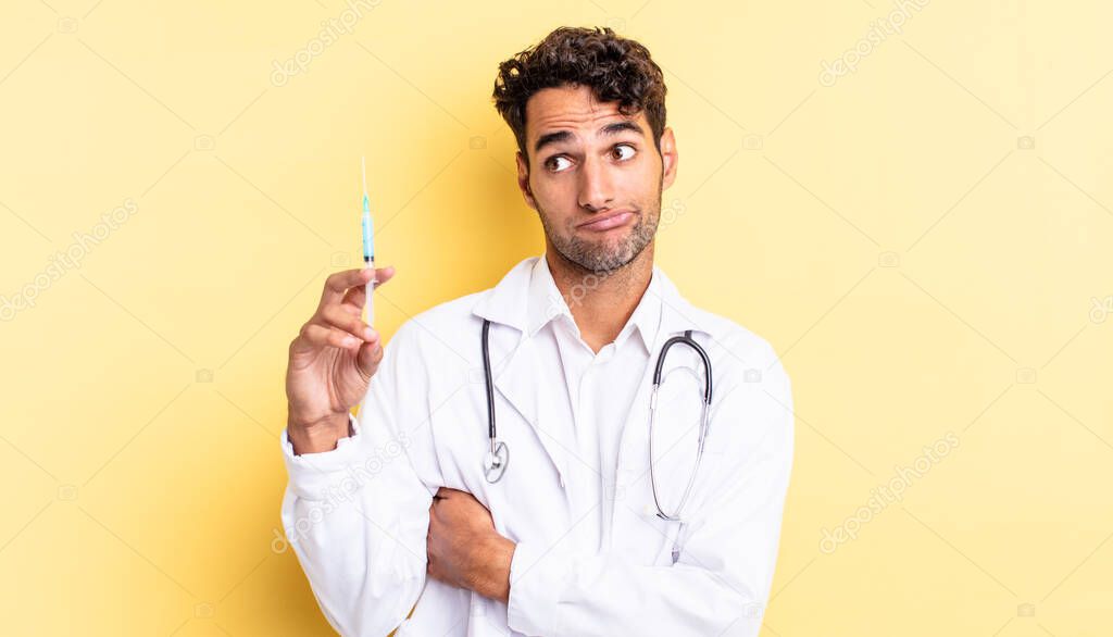 hispanic handsome man shrugging, feeling confused and uncertain physician and srynge concept