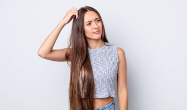 İspanyol güzel kadın şaşkın ve şaşkın hissediyor, başını kaşıyor ve yana bakıyor.