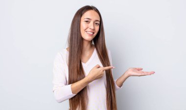 İspanyol güzel kadın gülümsüyor, mutlu, kaygısız ve tatmin olmuş hissediyor, fotokopi alanındaki konsepte ya da fikre işaret ediyor.