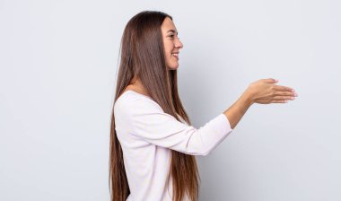 İspanyol güzel kadın gülümsüyor, seni selamlıyor ve başarılı bir anlaşma için el sıkışmayı teklif ediyor.