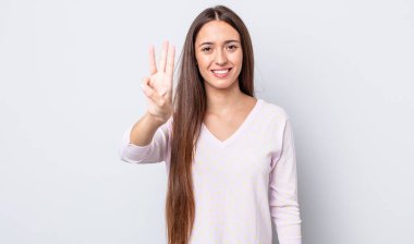 İspanyol güzel kadın gülümsüyor ve arkadaş canlısı görünüyor. Üç ya da üç numarayı gösteriyor. Elleri önde, geriye doğru sayıyor.