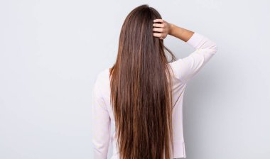 Hispanik güzel kadın düşünüyor ya da şüphe ediyor, kafasını kaşıyor, şaşkın ve şaşkın hissediyor, arkaya ya da arkaya bakıyor.