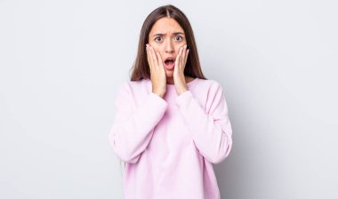 İspanyol güzel kadın şok olmuş ve korkmuş hissediyor, ağzı açık ve elleri yanaklarında korkmuş görünüyor.