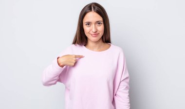 İspanyol güzel kadın gururlu, kendinden emin ve mutlu görünüyor, gülümsüyor ve kendini işaret ediyor ya da bir numara işareti yapıyor.