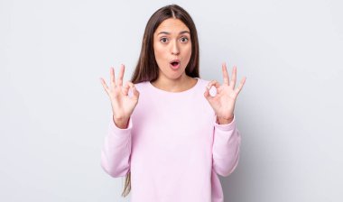 İspanyol güzel kadın şok olmuş, şaşırmış ve şaşırmış hissediyor. Onaylıyor. İki eliyle işaret veriyor.