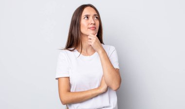 Hispanik güzel kadın düşünceli, meraklı ya da hayal kuruyor, hayal kuruyor ve uzayı kopyalamak için yukarı bakıyor.