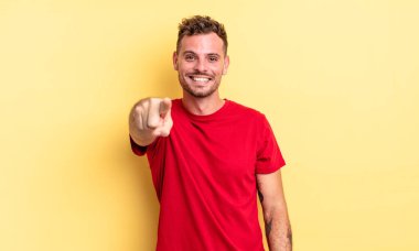 Genç, yakışıklı, İspanyol bir adam kameraya bakıyor. Tatmin olmuş, kendine güvenen, dost canlısı bir gülümsemeyle, seni seçiyor.