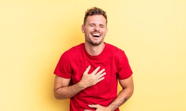 Genç, yakışıklı İspanyol bir adam komik bir şakaya yüksek sesle gülüyor, mutlu ve neşeli hissediyor, eğleniyor.