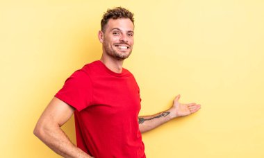 Genç, yakışıklı İspanyol adam kendini mutlu ve neşeli hissediyor, gülümsüyor ve seni hoş karşılıyor, seni dostça bir jestle içeri davet ediyor.