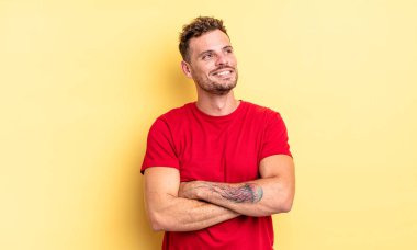 Genç, yakışıklı İspanyol adam kendini mutlu, gururlu ve umutlu hissediyor, merak ediyor ya da düşünüyor, çapraz kollarla fotokopi çekmeye çalışıyor.