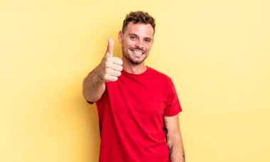 Genç, yakışıklı İspanyol adam gururlu, tasasız, kendinden emin ve mutlu, başparmağıyla olumlu gülümsüyor.